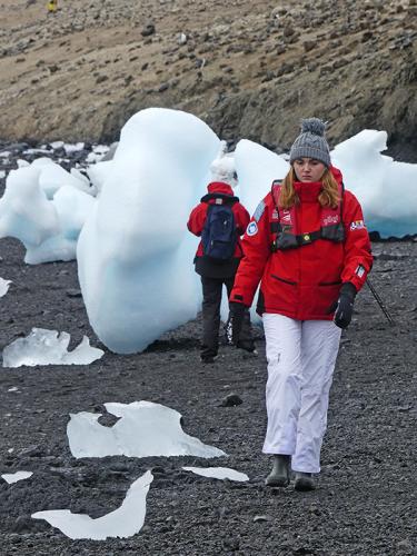 Elsa suit un manchot Adélie qui se déplace sur la plage de l'île du Diable, en respectant soigneusement la distance minimale de 5 mètres pour ne pas l'effrayer